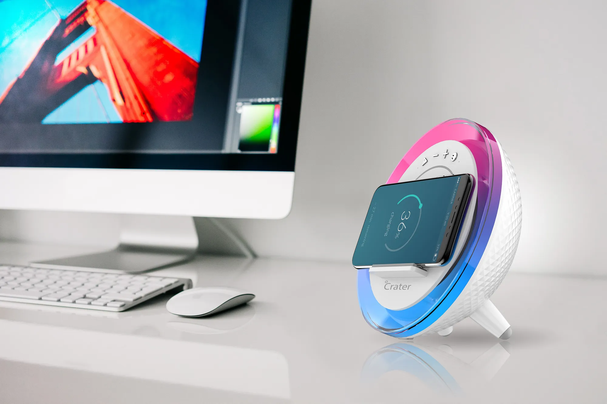 Okrúhly biely gadget s farebným podsvietením a smartfónom pri bezdrôtovom nabíjaní vedľa monitora a klávesnice